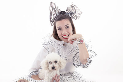 Portrait of young woman with dog against white background