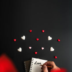 Midsection of person holding paper against black background