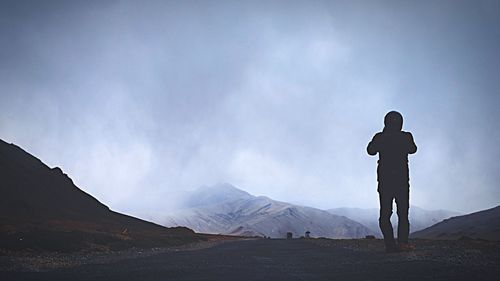 Silhouette man standing on mountain against sky