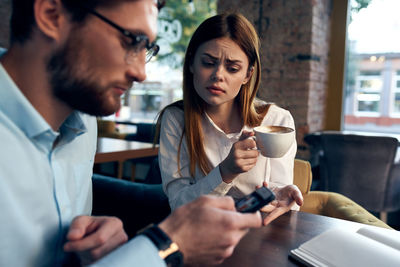 Young man holding coffee while sitting in cafe