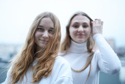 Portrait of smiling young girls standing against white background