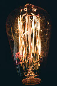 Close-up of illuminated light bulb against black background