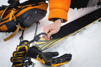 Close-up of a man's hand, adjusting the skis against the background of snow and things, putting on