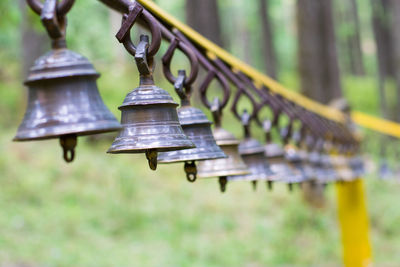 Close-up of metallic bells hanging in a line outside temple