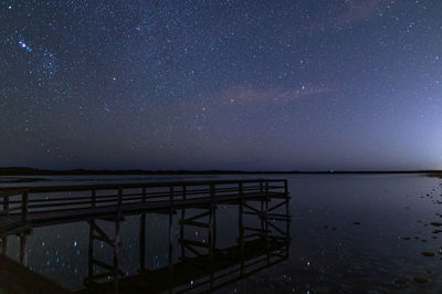 Pier over sea against sky at night