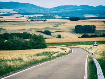 Small winding road through hills with road sign