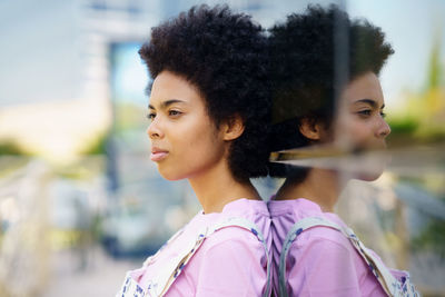 Young woman looking away while standing outdoors