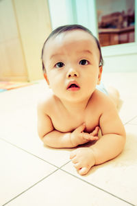 Cute baby crawling on tiled floor indoors