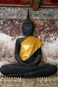 Statue of buddha against wall of building