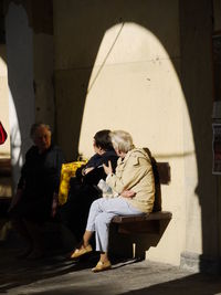 Young woman sitting against built structure