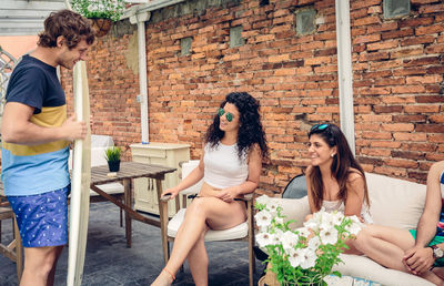 Young couple sitting on chair against brick wall