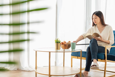 Young woman sitting on chair at home