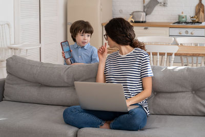 Mother scolding boy with mobile phone at home