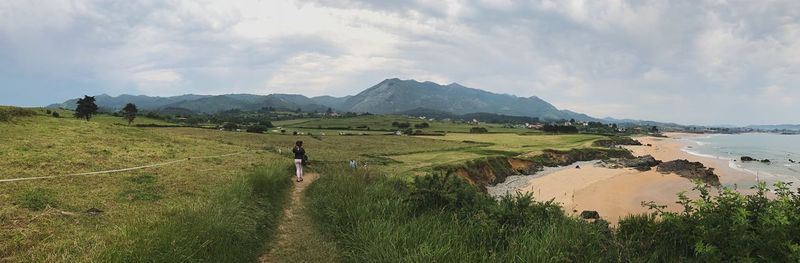 Mid distance view of person standing on grassy field against mountains