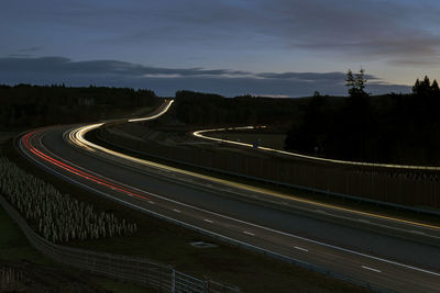 Light trails on road against sky at night