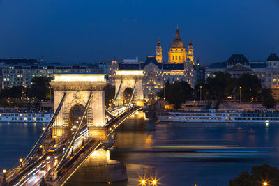 Illuminated bridge over river in city at night