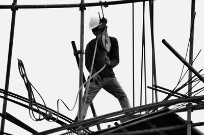 Low angle view of worker working at construction site against sky