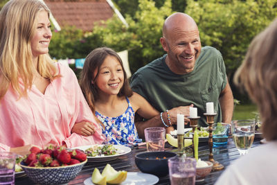 Playful man sitting with girls at dining table in back yard