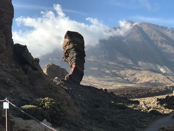 Rock formations on landscape against cloudy sky