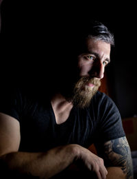 Portrait of man sitting against black background