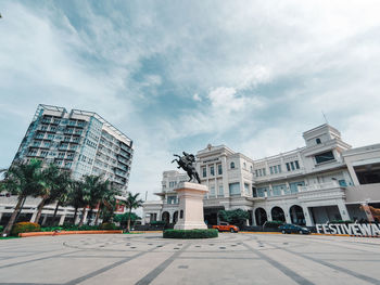 Statue by street against buildings in city against sky