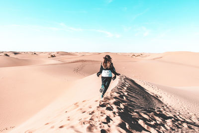 Rear view of man standing in desert against sky