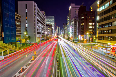 Light trails on city street amidst buildings at night