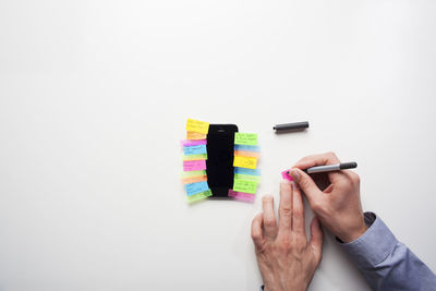 Midsection of person holding multi colored pencils against white background