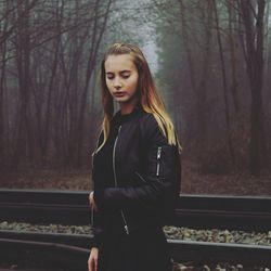 Young woman standing by bare trees in forest