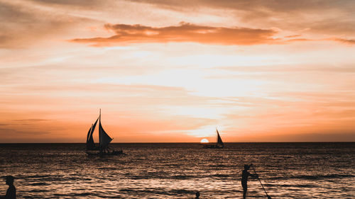 Silhouette man in sea against sky during sunset