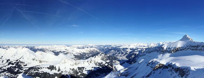 Scenic view of snowcapped mountains against blue sky