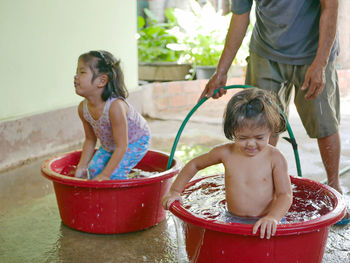 A baby girl, right, enjoys playing water in plastic basins with her older sister at home