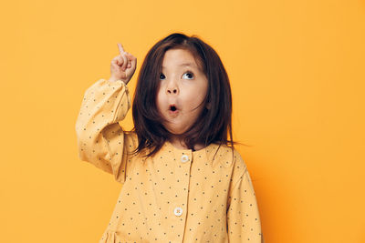 Girl pointing against yellow background