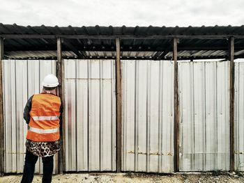 Rear view of worker standing against corrugated iron doors