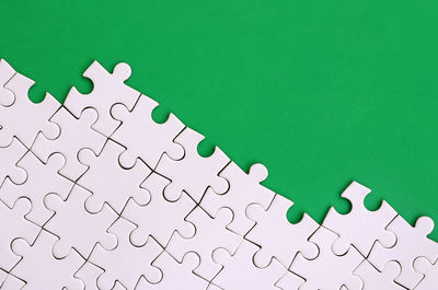 Full frame shot of white jigsaw puzzle against green background