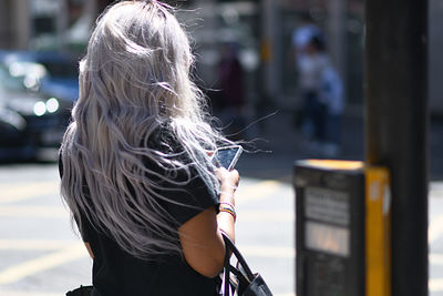 Rear view of woman with umbrella standing in city