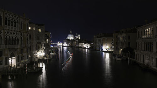 Canal amidst buildings in city at night