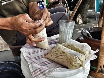 Midsection of man packing drinks in plastic bags 