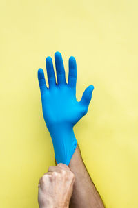 Close-up of hand against blue wall