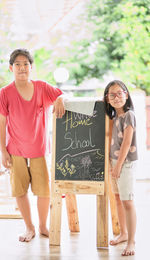 Portrait of smiling kids standing by board outdoors