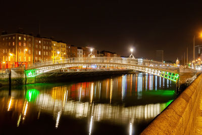 Illuminated bridge over river in city against sky at night