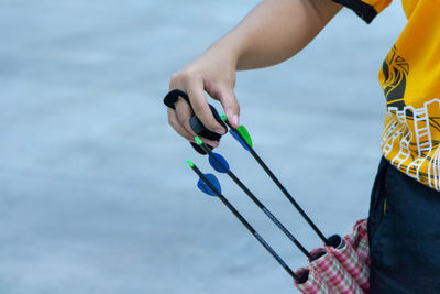 Midsection of person pulling arrow against sea