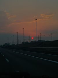 Cars on street against sky during sunset