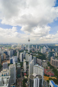 Aerial view of buildings in city against cloudy sky