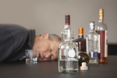 Reflection of man in glass bottle on table