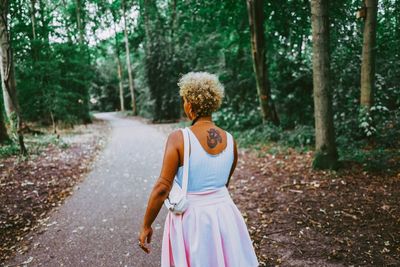 Full length of woman on road amidst trees in forest