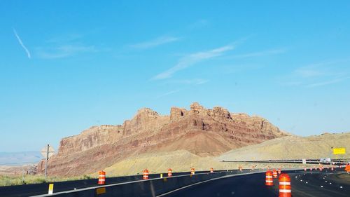 Road leading towards mountains against blue sky