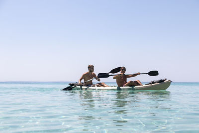 Happy two teenagers kayaking together in amazing clear water of aegean family adventures concept