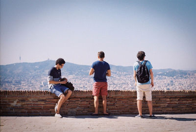 Boys standing on shore against sky