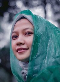Close-up portrait of smiling young woman wearing raincoat